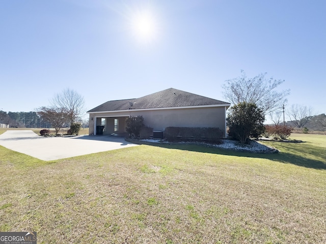 back of property featuring concrete driveway and a lawn