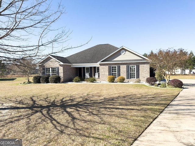 view of front of home featuring brick siding, a front lawn, and a shingled roof