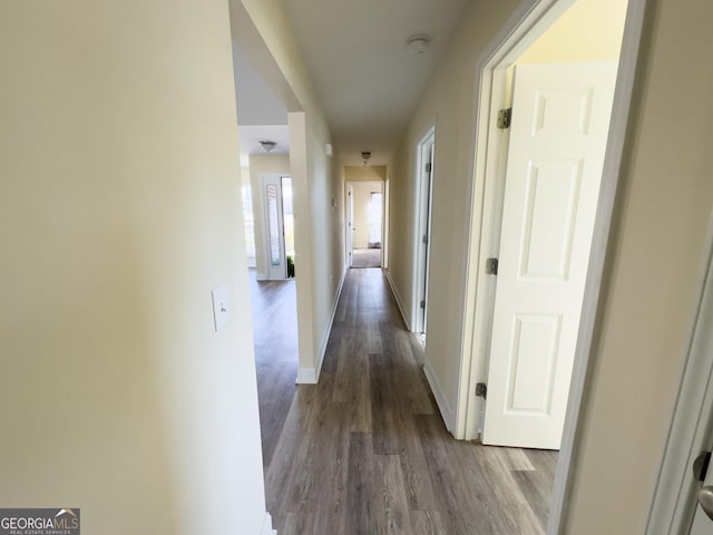 hallway featuring dark wood-style flooring and baseboards