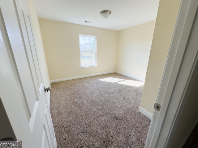 carpeted spare room featuring baseboards and visible vents