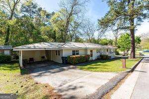 ranch-style house featuring a front lawn, aphalt driveway, and a carport