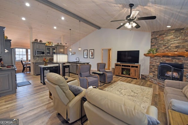 living area featuring wooden ceiling, a fireplace, wood finished floors, a ceiling fan, and beam ceiling