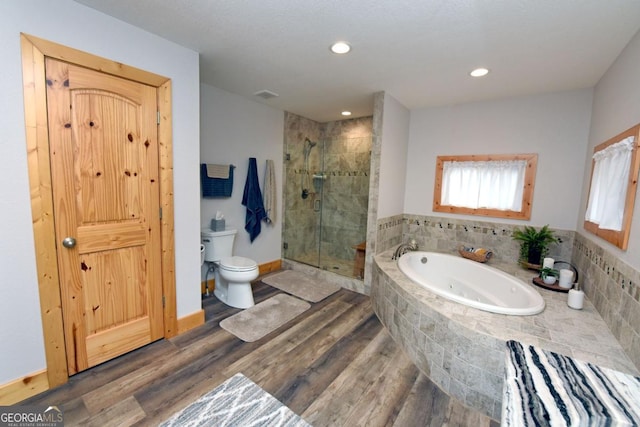 bathroom with a stall shower, wood finished floors, toilet, and a bath