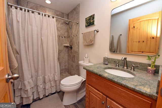 full bath featuring tiled shower, vanity, and toilet