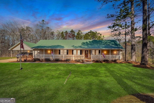 farmhouse inspired home with metal roof, a yard, and a porch