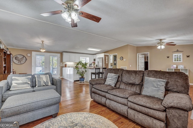 living room with vaulted ceiling, ornamental molding, light wood-type flooring, and baseboards