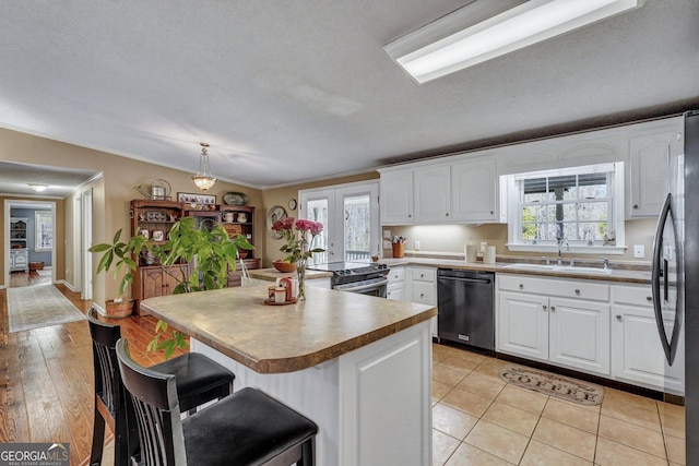 kitchen featuring white cabinetry, stainless steel appliances, a sink, and a kitchen breakfast bar