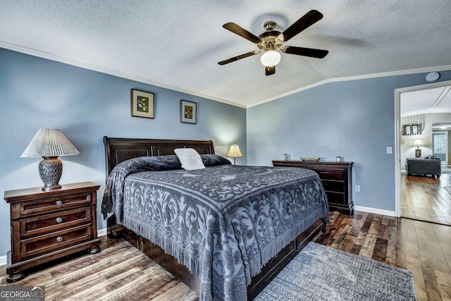 bedroom featuring lofted ceiling, a textured ceiling, baseboards, wood-type flooring, and crown molding