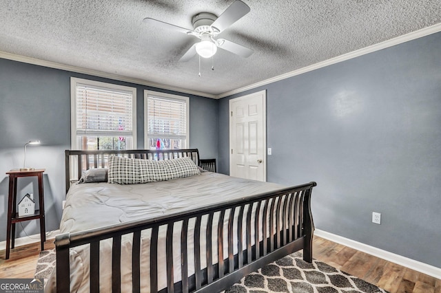 bedroom with a textured ceiling, ornamental molding, wood finished floors, and baseboards