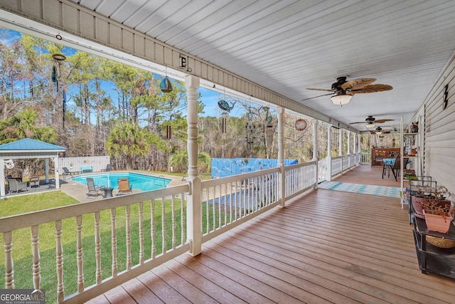 wooden deck with a fenced in pool, a ceiling fan, a lawn, fence, and a gazebo