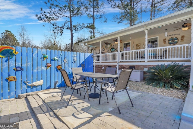 view of patio featuring a ceiling fan, outdoor dining space, and fence