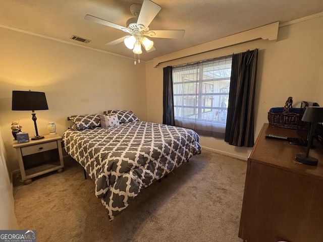 carpeted bedroom with ornamental molding, visible vents, and a ceiling fan