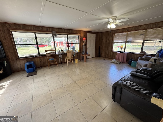 living area featuring plenty of natural light, wood walls, and ceiling fan