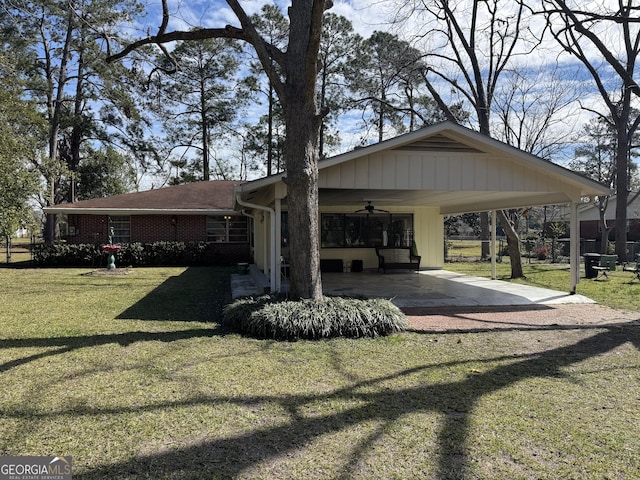 exterior space featuring brick siding, a ceiling fan, a yard, driveway, and a carport