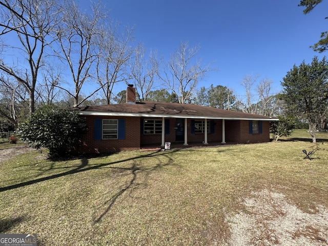 ranch-style home featuring covered porch, brick siding, a chimney, and a front yard