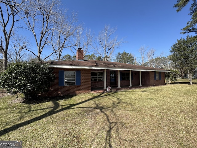 single story home featuring a porch, brick siding, a chimney, and a front lawn