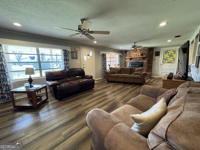 living area with baseboards, ornamental molding, dark wood-type flooring, a textured ceiling, and a fireplace