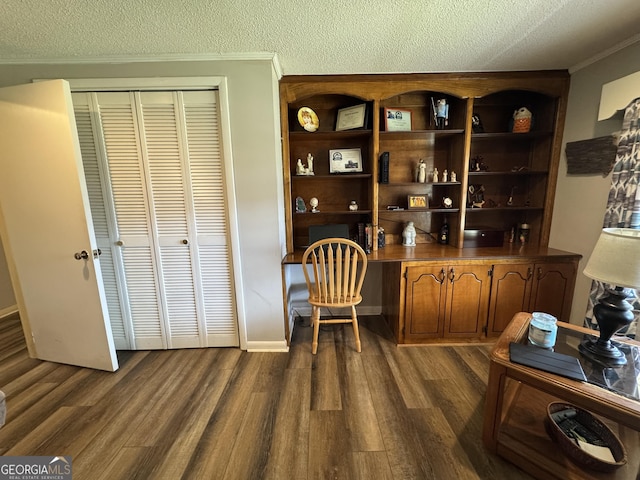 office space with dark wood-style floors, built in desk, a textured ceiling, and ornamental molding