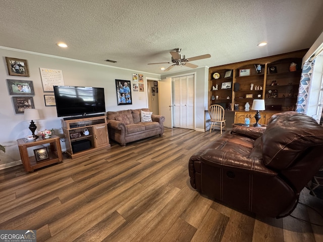 living area featuring visible vents, ceiling fan, ornamental molding, wood finished floors, and a textured ceiling