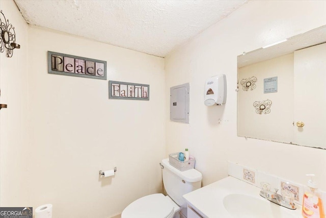 half bath featuring electric panel, a textured ceiling, toilet, and vanity