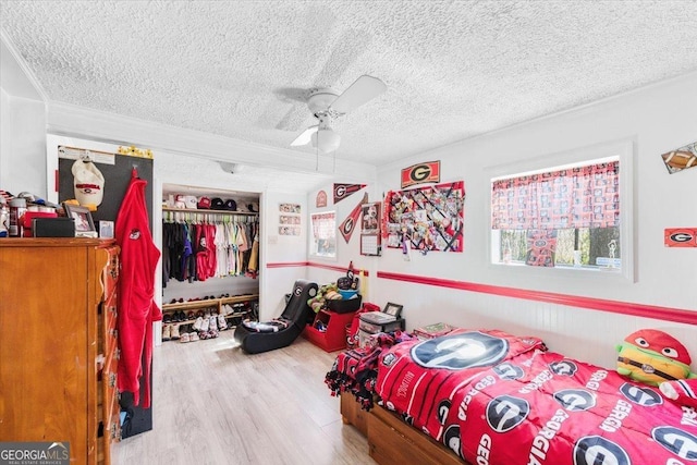 bedroom with a ceiling fan, a closet, a textured ceiling, and wood finished floors