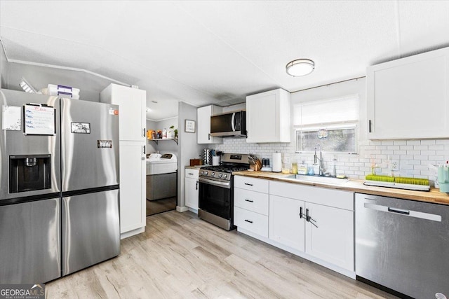 kitchen featuring a sink, white cabinetry, light wood-style floors, appliances with stainless steel finishes, and decorative backsplash