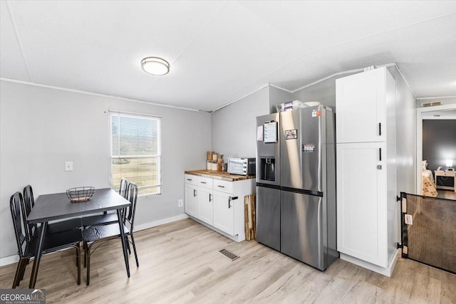 kitchen featuring light wood-type flooring, butcher block counters, stainless steel refrigerator with ice dispenser, and white cabinetry