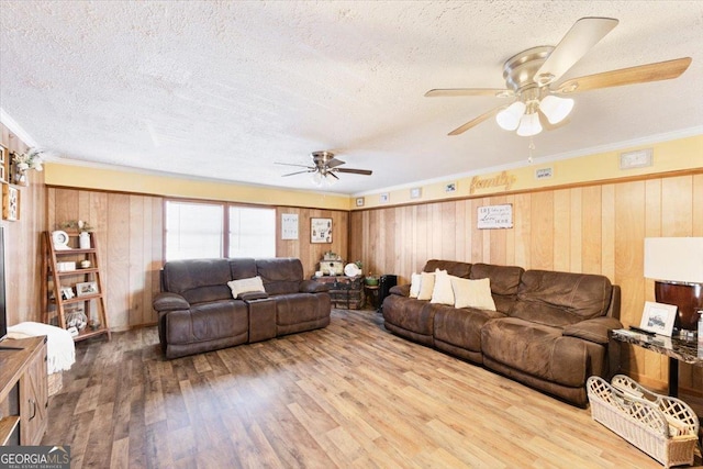 living area with ornamental molding, a textured ceiling, wooden walls, and wood finished floors