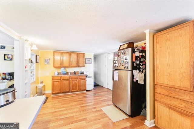 kitchen featuring light countertops, freestanding refrigerator, a textured ceiling, light wood-type flooring, and baseboards