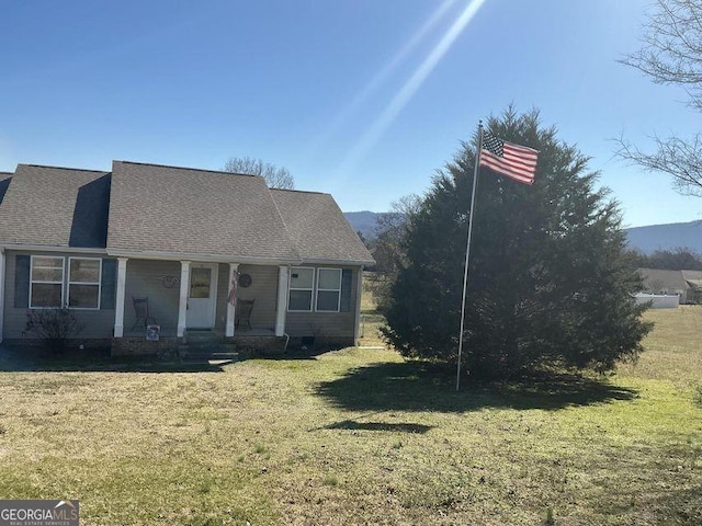 view of front of property featuring a front yard, covered porch, and roof with shingles