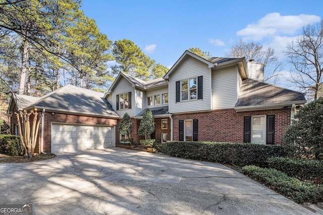 traditional-style home with a garage, concrete driveway, brick siding, and a chimney