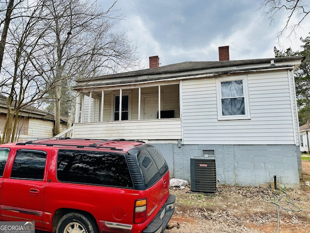 exterior space featuring a porch, crawl space, a chimney, and central air condition unit