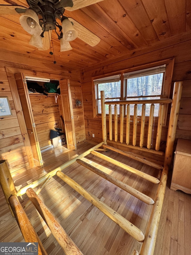 unfurnished bedroom featuring wood ceiling, wooden walls, a sauna, multiple windows, and hardwood / wood-style floors