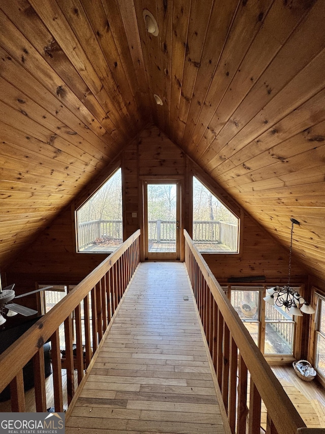 additional living space featuring a chandelier, wooden walls, wood ceiling, vaulted ceiling, and wood-type flooring