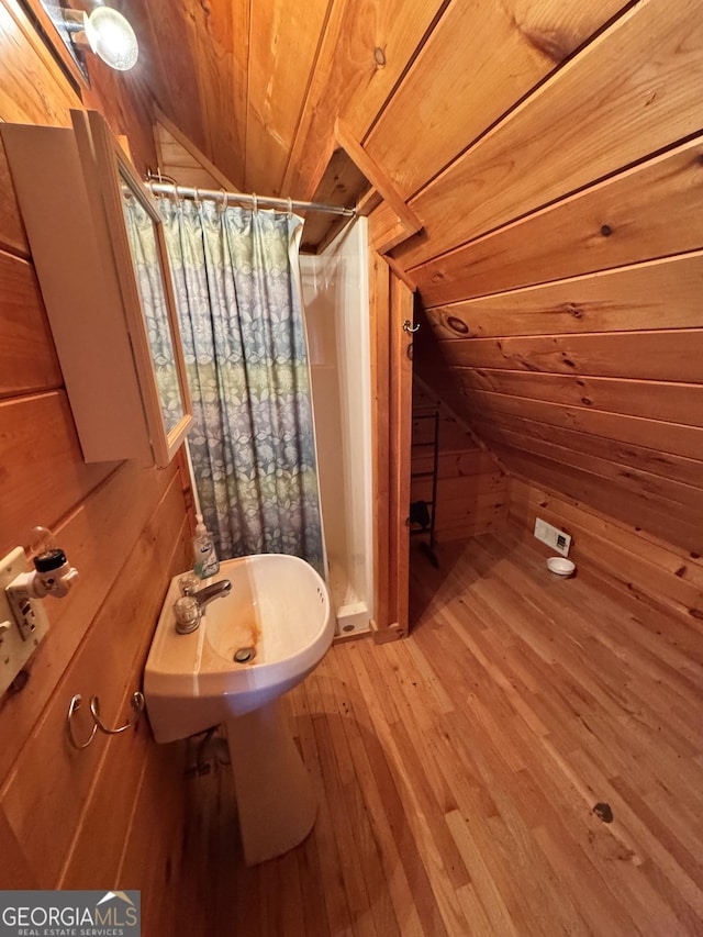 full bath featuring lofted ceiling, wooden ceiling, wood walls, a shower stall, and wood-type flooring