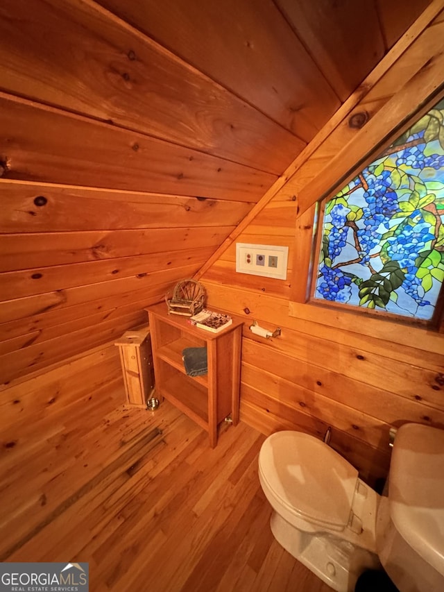 bathroom featuring toilet, wood ceiling, vaulted ceiling, wood walls, and wood finished floors