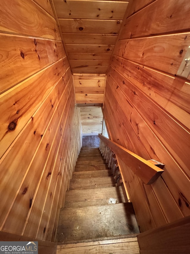 stairs with wood walls, wood ceiling, and wood-type flooring