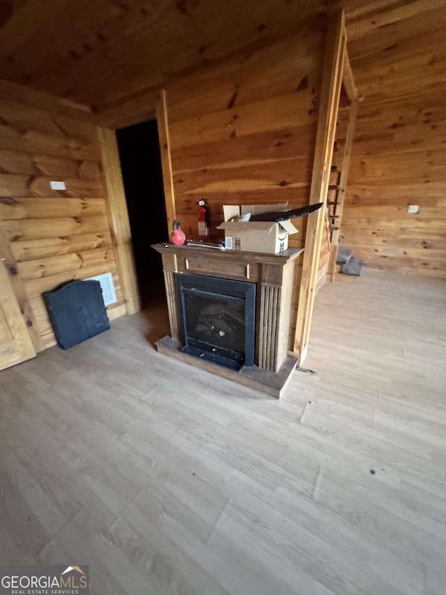 unfurnished living room with wood walls, a fireplace, and wood finished floors