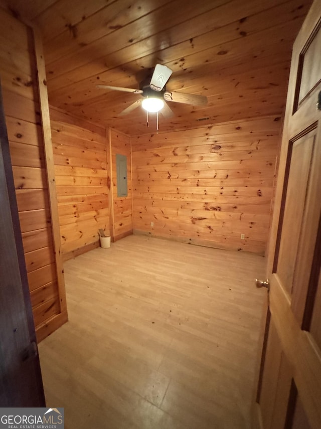 empty room featuring wooden ceiling, electric panel, wood walls, and light wood-style flooring