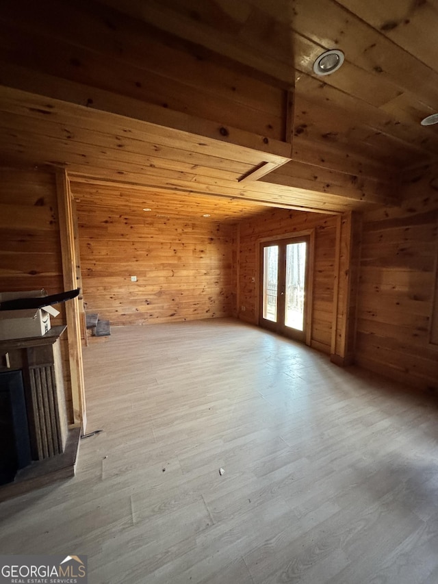 additional living space featuring light wood finished floors, a fireplace, and wooden walls