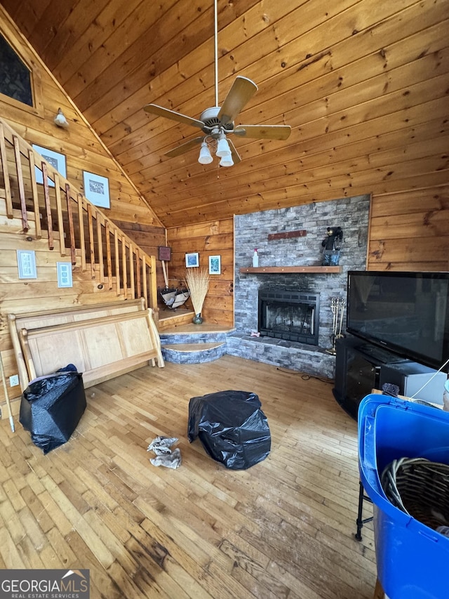 unfurnished living room with lofted ceiling, hardwood / wood-style floors, stairway, and wooden walls