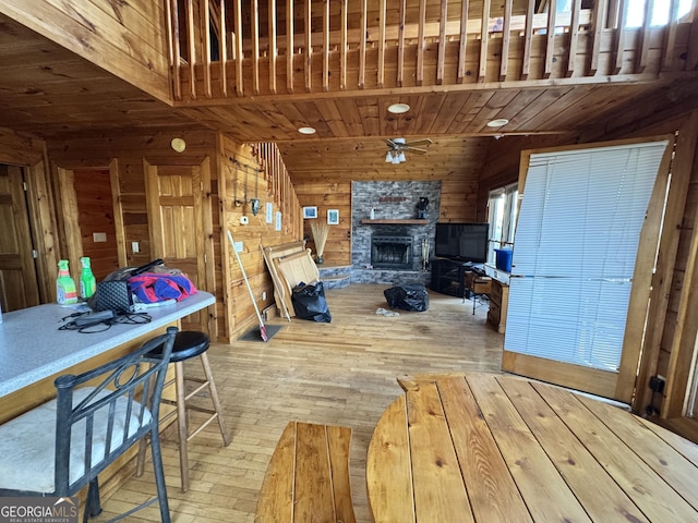 interior space with ceiling fan, wooden ceiling, wooden walls, a fireplace, and wood finished floors