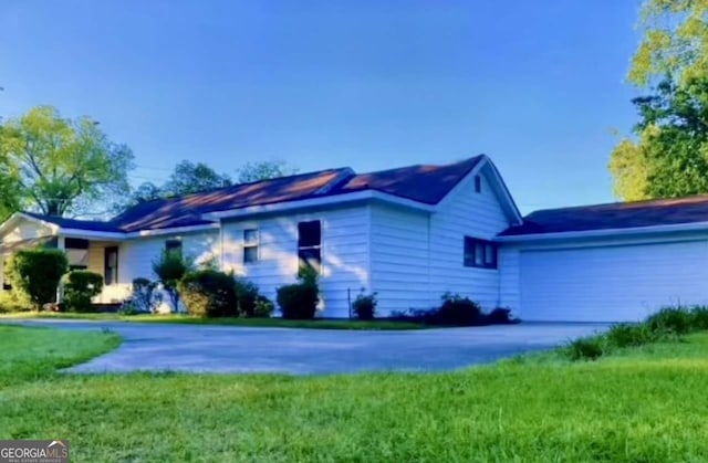 single story home featuring a garage, a front lawn, and aphalt driveway