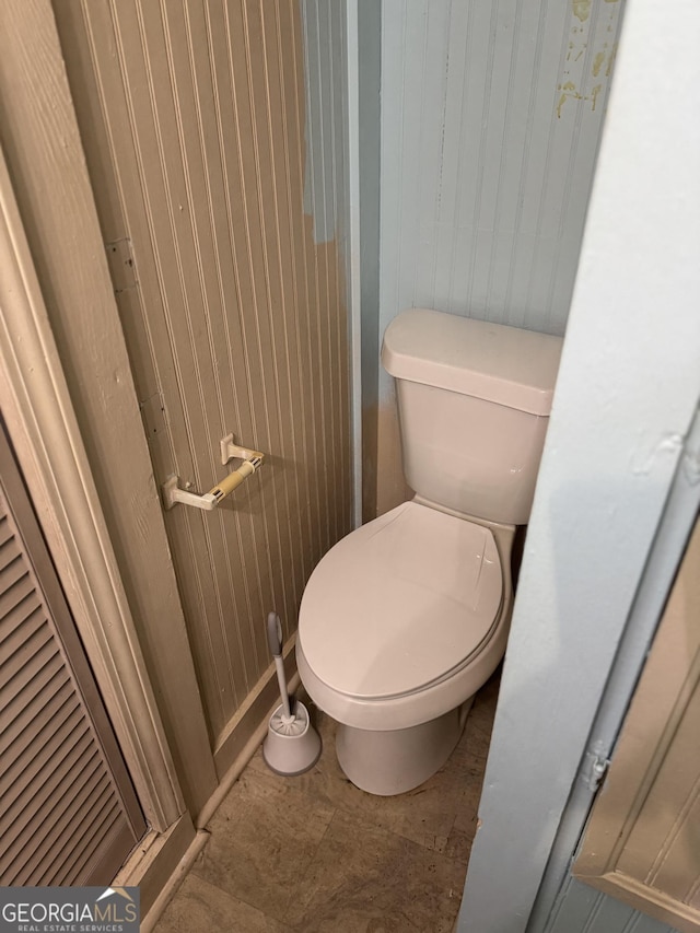 bathroom with wood walls and toilet