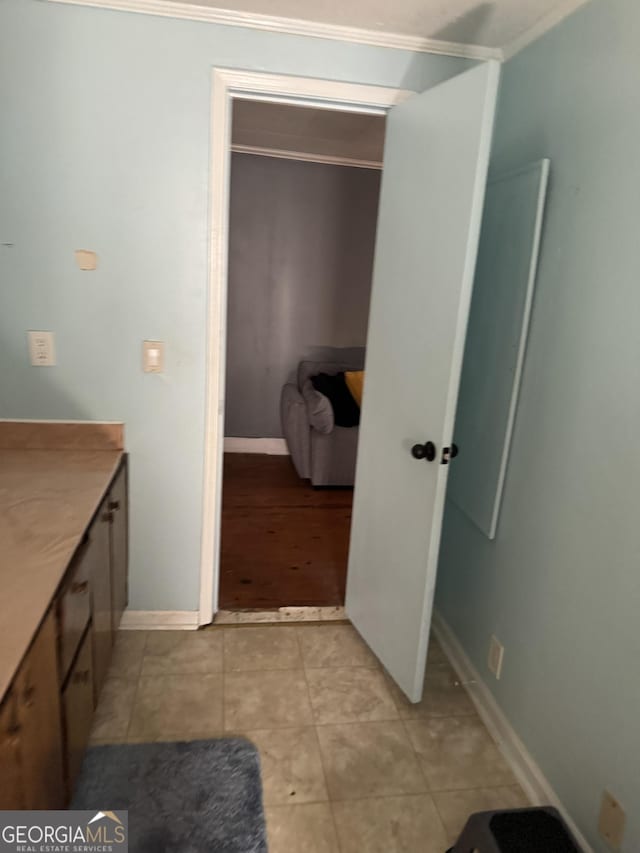 bathroom with tile patterned flooring, crown molding, vanity, and baseboards