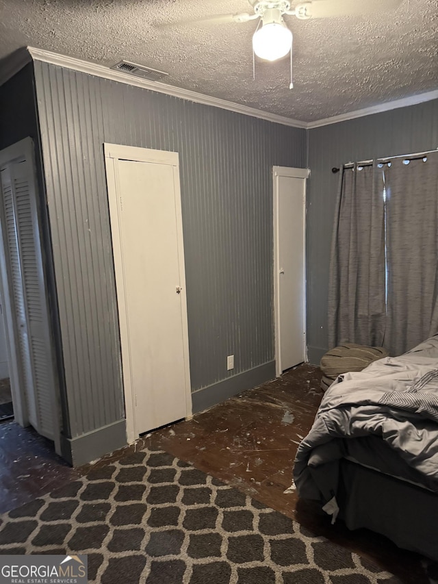 bedroom featuring ornamental molding, visible vents, a textured ceiling, and a ceiling fan