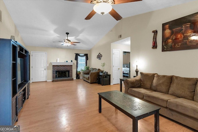 living room with light wood-style floors, lofted ceiling, a brick fireplace, and a ceiling fan