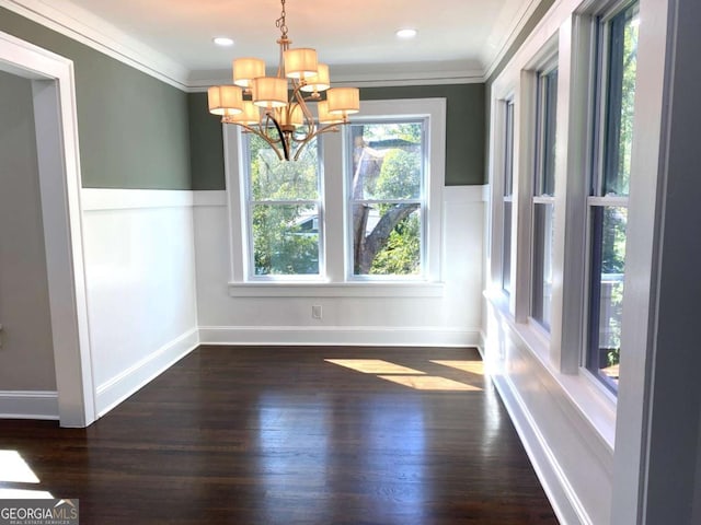 unfurnished dining area with a chandelier, ornamental molding, wainscoting, and dark wood finished floors