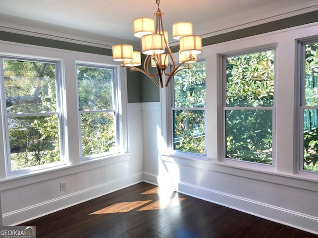 unfurnished dining area with a healthy amount of sunlight, baseboards, dark wood-type flooring, and a notable chandelier