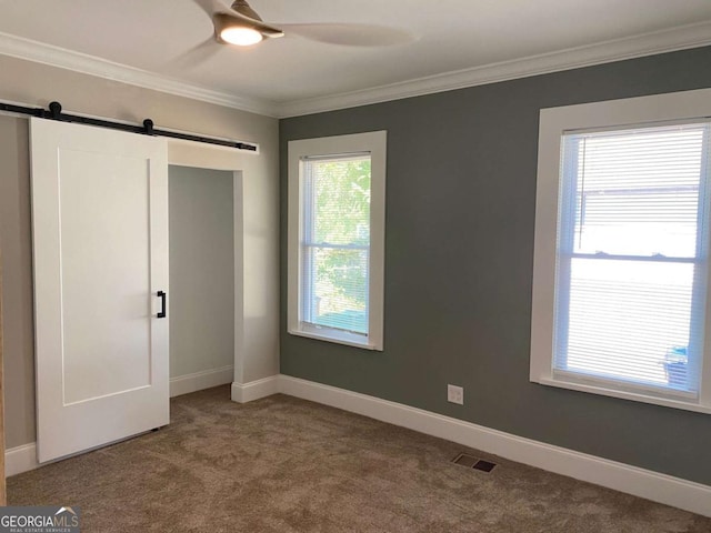 unfurnished bedroom with ornamental molding, carpet flooring, and a barn door